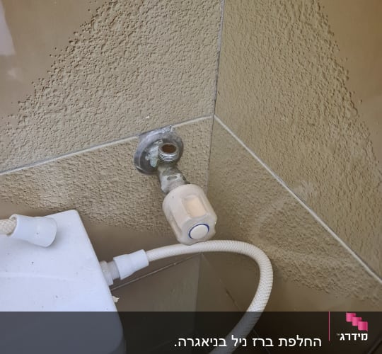 ברז מים עם צינור מחובר על קיר קרמיקה